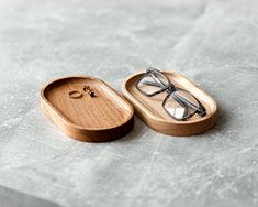 a pair of glasses sitting on top of a wooden box with a ring in it