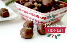 chocolate covered candies in a red and white bowl on a table with holly decorations