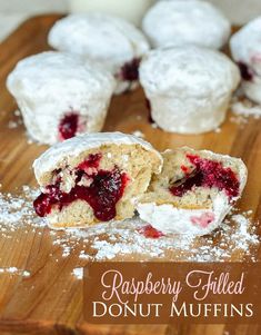 raspberry filled donut muffins on a cutting board with powdered sugar