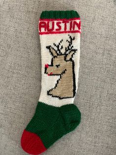 a knitted christmas stocking with a reindeer head on it's side and the word, rustin written in red