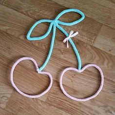 two hearts are tied together on a wooden floor with a blue string attached to them