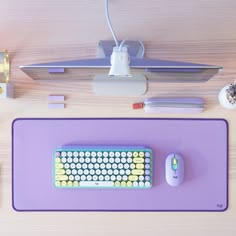 a computer keyboard and mouse sitting on top of a purple mat next to other office supplies