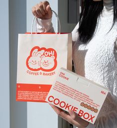 a woman holding up a cookie box bag