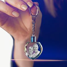 a woman holding a keychain with an image of two people on it in front of her