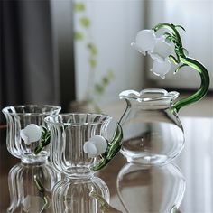 three glass vases with flowers in them sitting on a table next to each other