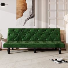 a living room with a green couch in the middle and a painting on the wall