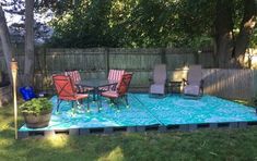 a patio with chairs and a table in the middle of it, surrounded by grass