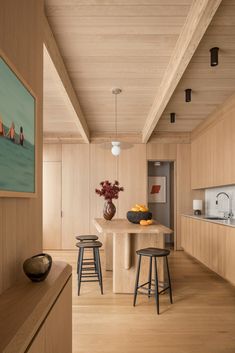 a kitchen with wooden walls and flooring next to a dining room table surrounded by stools