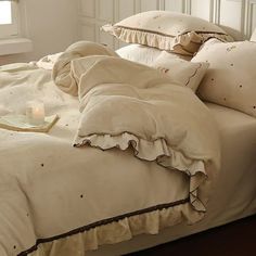 an unmade bed with white sheets and brown ruffles on the comforter