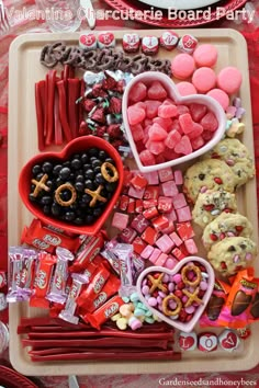 valentine's day treats are arranged on a tray with candy, candies and cookies