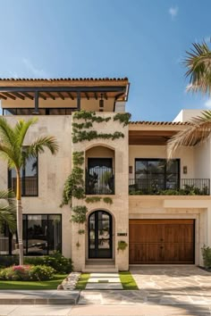 a large white house with lots of windows and plants on the front door, along with palm trees