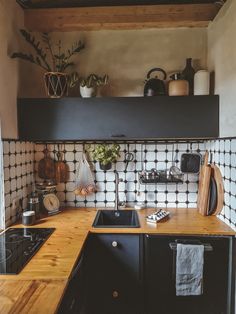 a kitchen with black and white tiles on the wall, wooden counter tops and cabinets