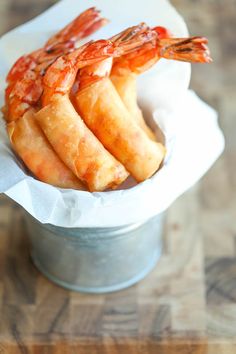 some shrimp sticks are in a bucket on a wooden table and is ready to be eaten