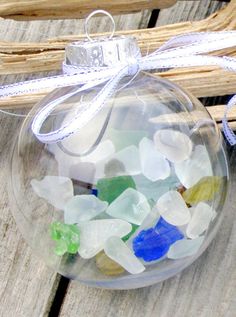 a glass ornament filled with sea glass sitting on top of a wooden table