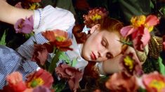 a woman laying on the ground surrounded by flowers