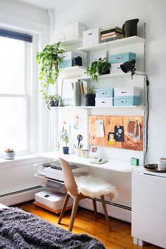 a white desk and chair in a room with shelves on the wall above it, along with various office supplies