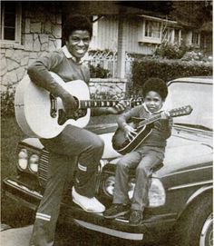 an old black and white photo of two boys playing guitar in the back of a car