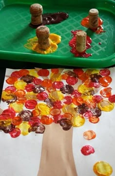 a child's hand is painting a tree with gummy bears on the paper