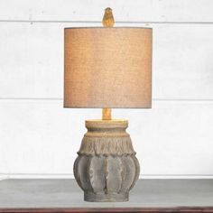 a table lamp sitting on top of a wooden table next to a white brick wall