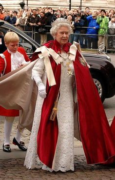 an older woman dressed in red and white walking down the street with other people behind her