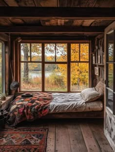 a bed sitting in the middle of a room next to a window with lots of windows