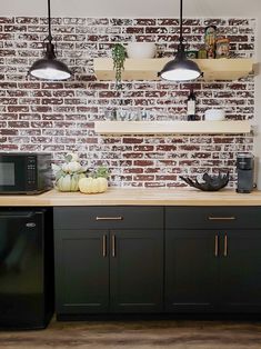 a kitchen with black cabinets and white brick wall