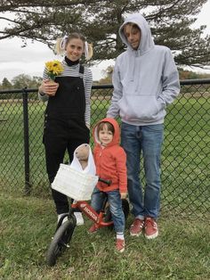 two adults and a child standing in front of a fence