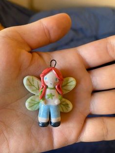 a hand holding a small ceramic fairy ornament in it's left hand