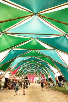 the inside of a tent with people walking under it and lots of green umbrellas