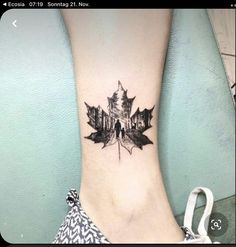 a woman's foot with a black and white maple leaf tattoo on the ankle