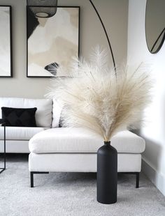 a white couch sitting next to a tall black vase