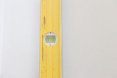 a yellow and white clock mounted to the side of a wall