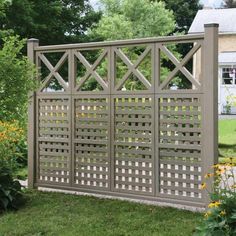 a wooden fence in the middle of some grass and flowers with yellow flowers around it