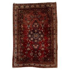 an antique persian rug with red and blue colors on the bottom, surrounded by floral designs