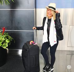 a woman standing next to a black suitcase