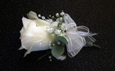 a white rose and baby's breath boutonniere on a black background