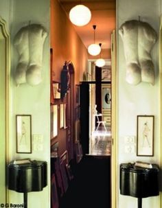 an open door leading to a hallway with pictures on the wall and lamps hanging from the ceiling