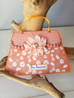 an orange and pink purse sitting on top of a tree branch