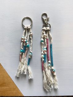 two key chains with beads and tassels hanging from them on a table top