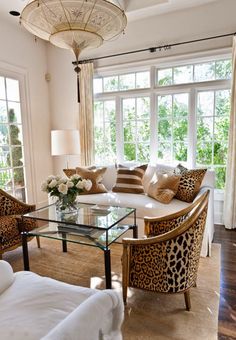 a living room with couches, chairs and a table in front of two windows