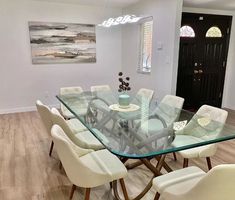 a glass dining table with white chairs in a room