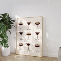 an art print with martini glasses on it in front of a potted plant