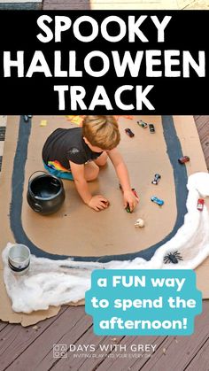 preschooler driving small race cars around a cardboard racetrack. The racetrack has Halloween decorations such as spider webs and plastic spiders Washable Paint