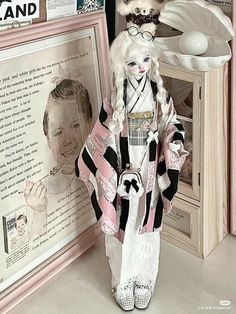 a doll is standing next to a framed photo