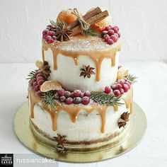 a three tiered cake covered in icing and topped with berries, cinnamons, star anisettes and spices