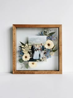 a wooden frame with flowers and photos on the inside is holding a couple's wedding photo