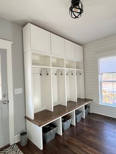 an empty room with white cabinets and wooden floors in the center is filled with storage bins