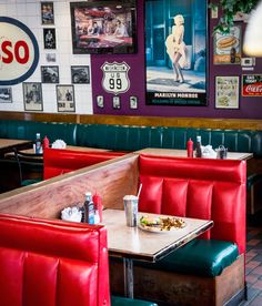 the inside of a restaurant with booths and tables in front of posters on the wall