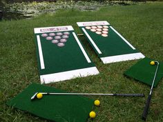 two cornhole game boards on the grass with golf balls and tees next to it