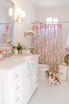 a dog is standing in the bathroom next to the sink and shower curtain that has pink flowers on it